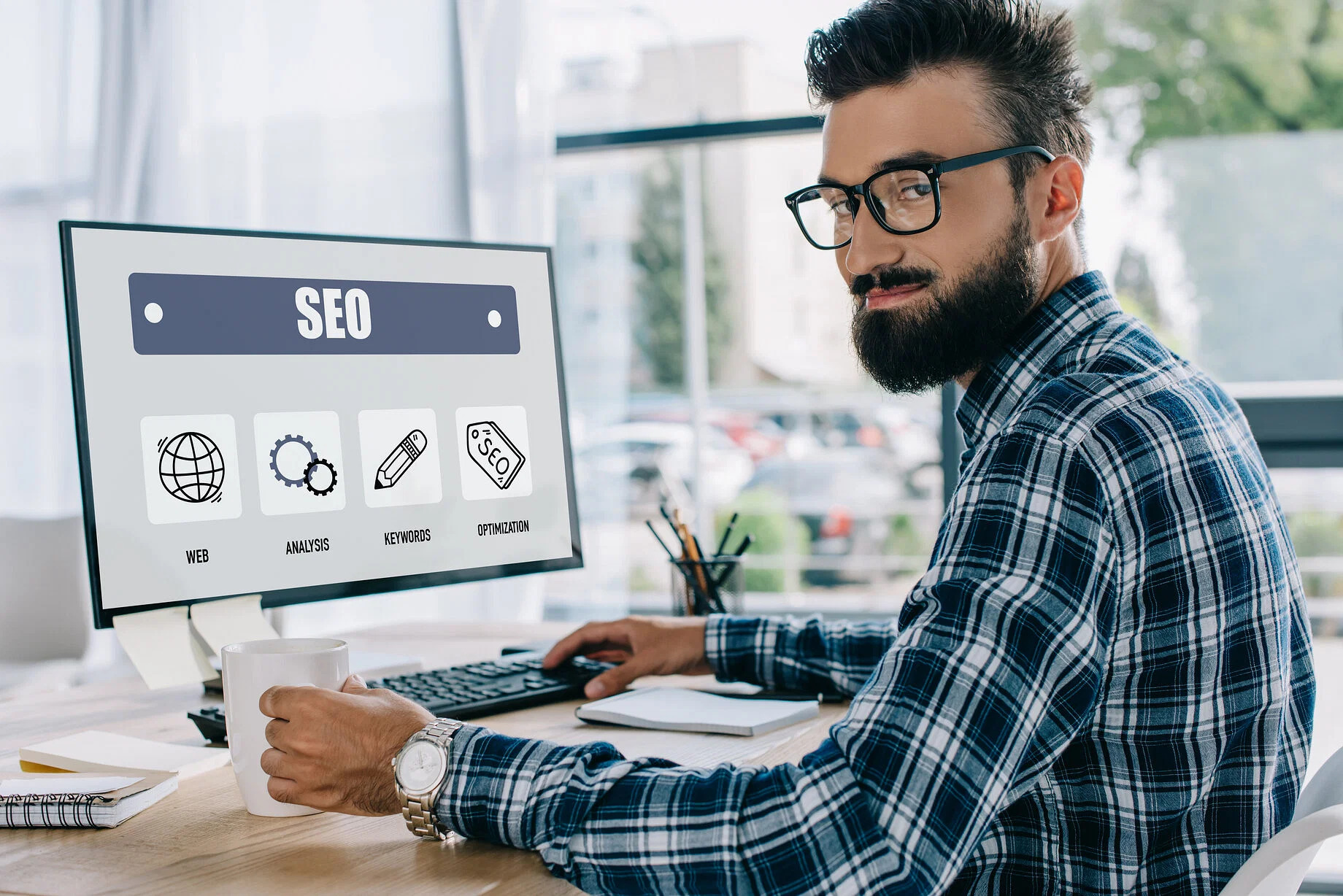 A man sitting in front of a computer screen with seo icons on it.