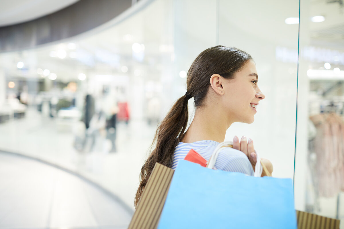 A young woman holding shopping bags in a mall.