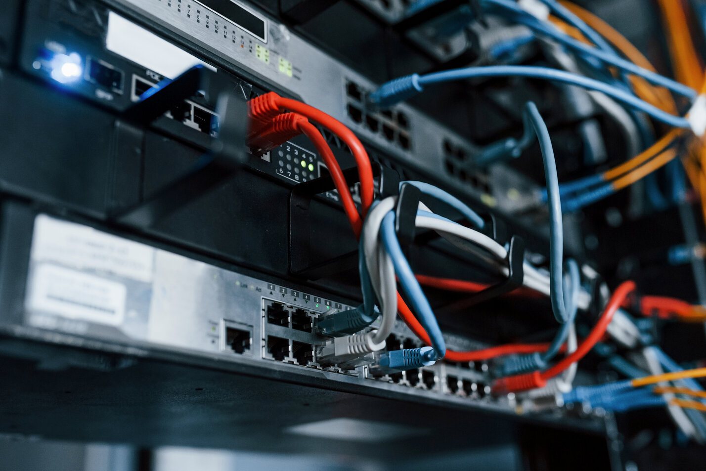 A close up of a server rack with wires and cables.