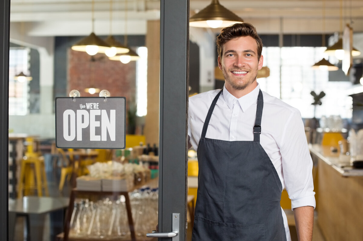 Portrait of smiling owner standing at his restaurant gate need for digital marketing services