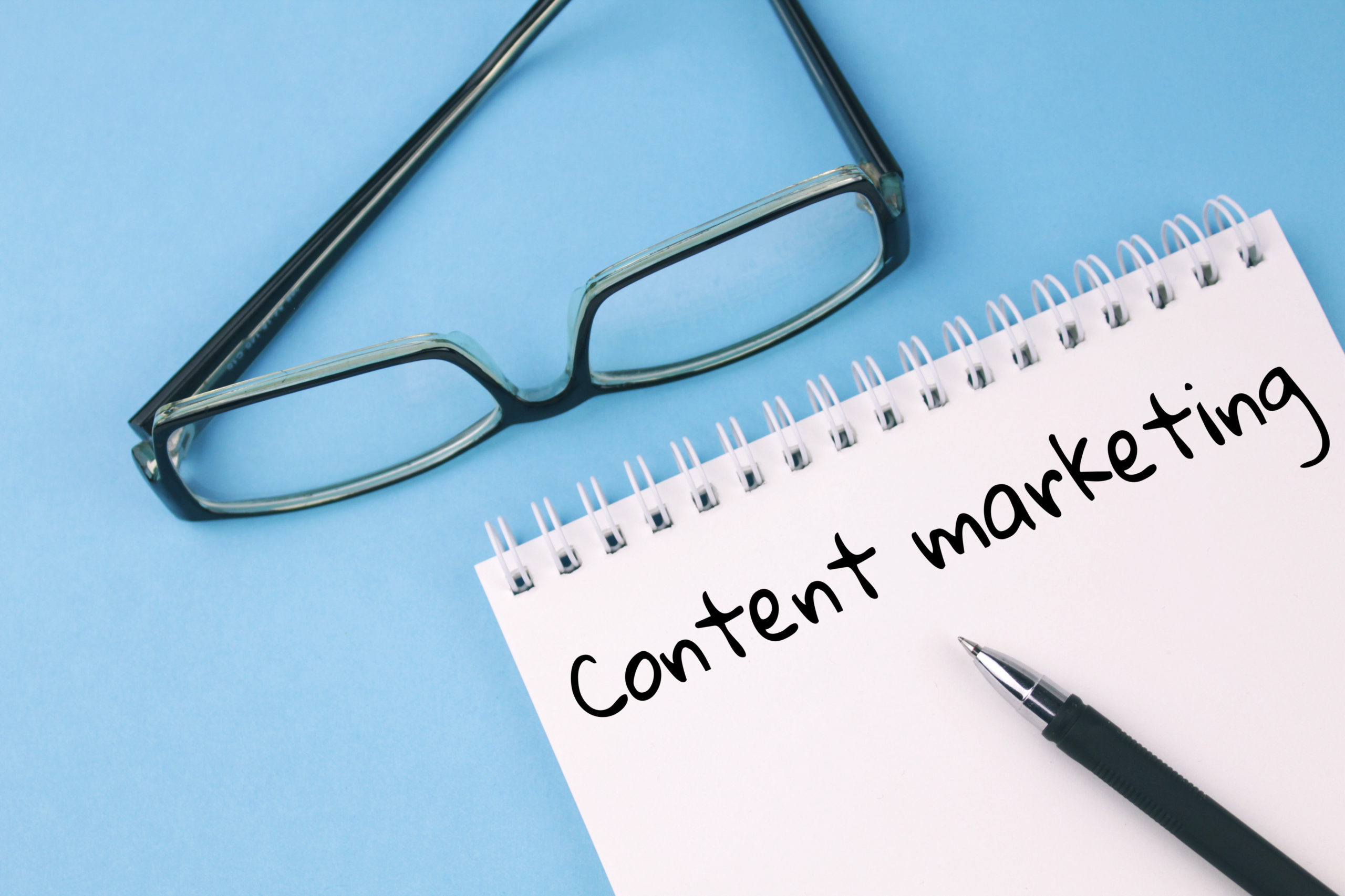 A notepad featuring the term "content marketing" alongside glasses and a pen.