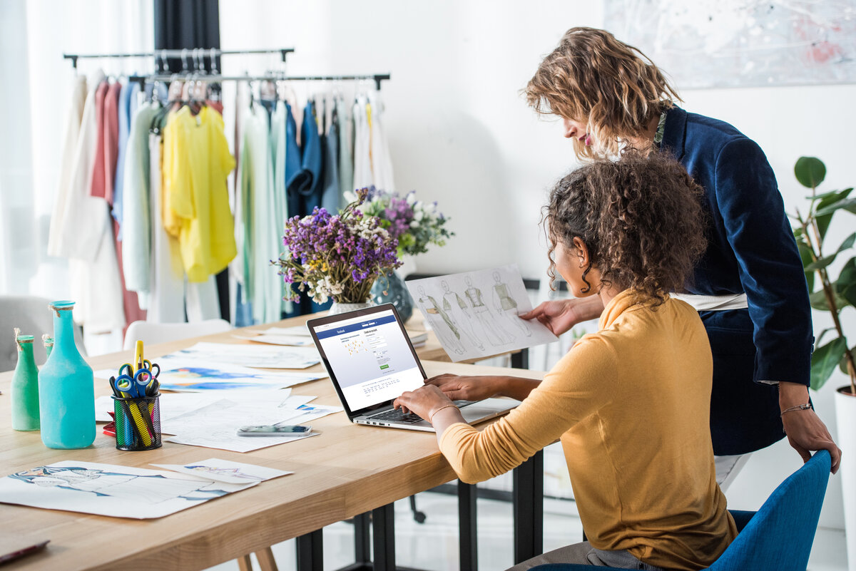 young fashion designers using laptop with facebook website on screen