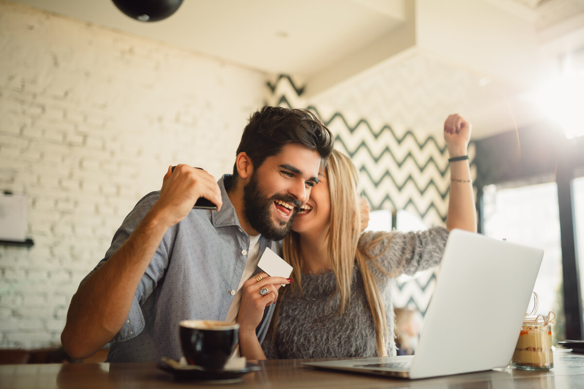 Happy couple shopping online in cafeteria.